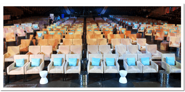 large meeting space with beige chairs and blue pillows facing a stage